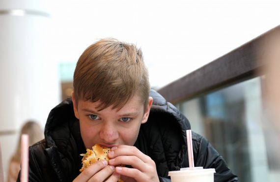 Teenager isst Hamburger