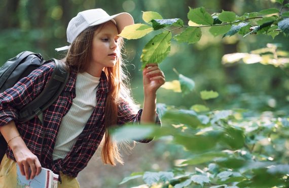 Mädchen betrachtet Blätter im Wald