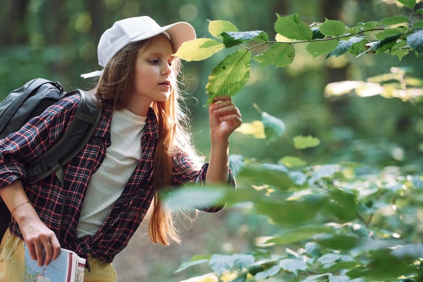 Mädchen betrachtet Blätter im Wald