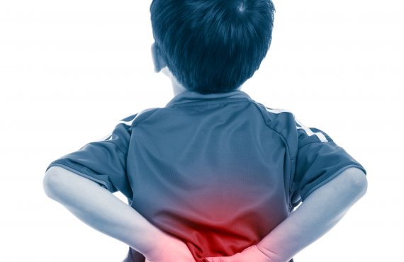 Junge hält sich Rücken aufgrund von Schmerzen