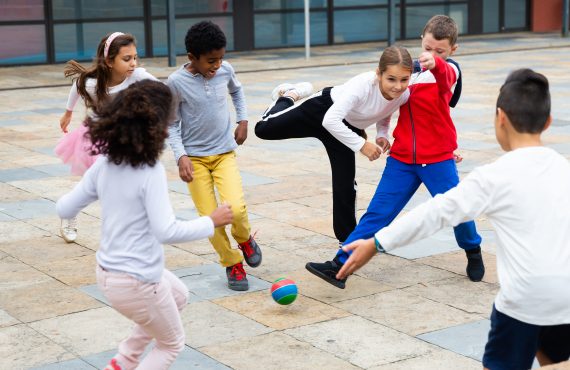Gruppe aktiver Schüler, die am Sommertag Fußball spielen