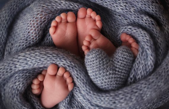 Füße von drei Neugeborenen in einer weichen Decke.