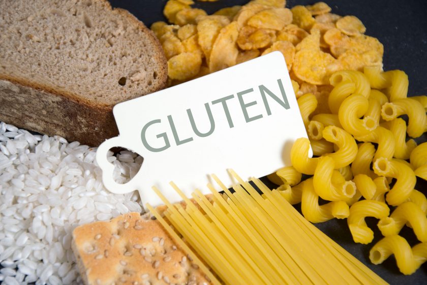 Schild mit Aufschrift Gluten vor Brot, Reis und Pasta
