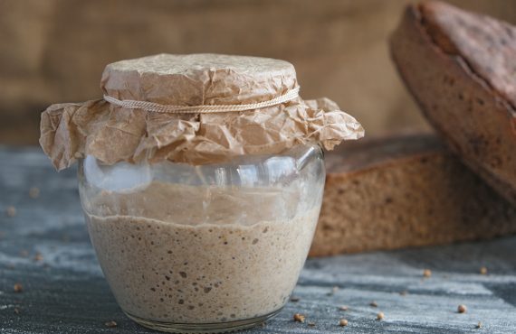 frischer Roggensauerteig im Glas und Laib Vollkornbrot