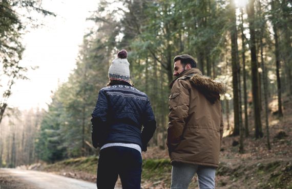 Rückansicht von Vater und Sohn beim Spazierengehen im Herbstwald
