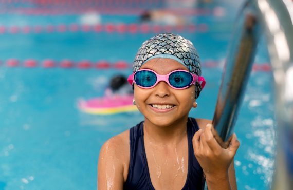 Glückliches Kind genießt Schwimmunterricht im Schwimmbad